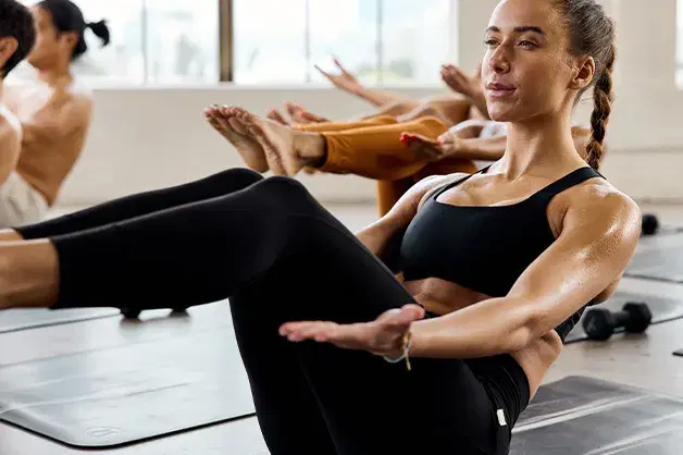 Yogi in a hollow boat pose wearing an all black workout set during a 澳洲幸运10开奖官网开奖 Yoga sculpt class