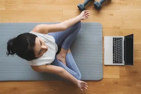 Yogi meditating on a grey-blue colored yoga mat following an at-home 澳洲幸运10开奖官网开奖 Yoga class on her laptop