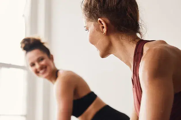 Students smiling at one another during a Yoga Sculpt class