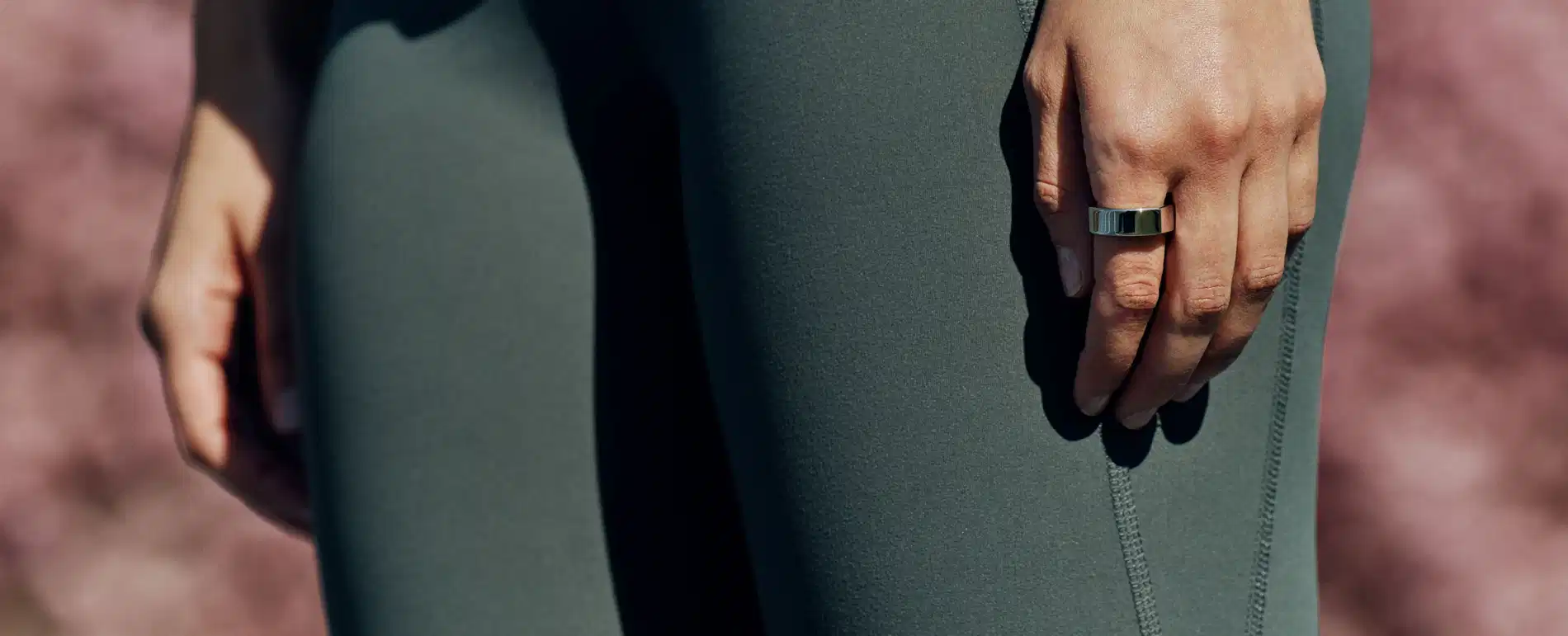 Woman wearing forest green leggings with her hands and arms by her side with a silver Oura Ring on her index finger